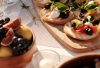 Sunlit outdoor table with Mediterranean bruschetta and fresh fruit display.