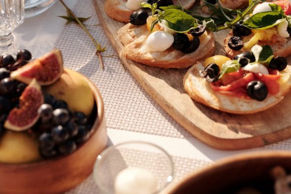 Sunlit outdoor table with Mediterranean bruschetta and fresh fruit display.